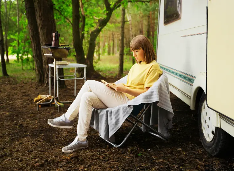 A Women Sitting on Chair Reading Full Time RV Living for Beginners Guide