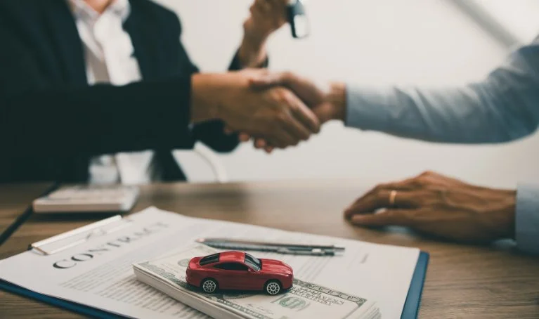 Handshake representing a car sale agreement with cash, contract, and keys, illustrating aspects of Wdroyo auto insurance coverage and services in 2024.